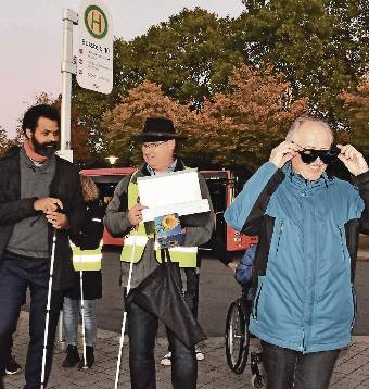 Eine Person verteilt Simulationsbrillen an zwei weitere Personen.